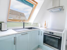 A kitchen corner with a sink under a slanted window a kettle and an oven at Kingfisher in Isleham