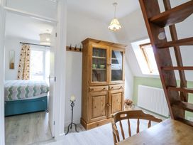 A room with a wooden cabinet a wooden chair and table and an open door to a bedroom at Kingfisher Isleham
