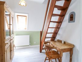 A small room with wooden stairs a wooden desk and chair a wooden wardrobe and a window at Kingfisher in Isleham