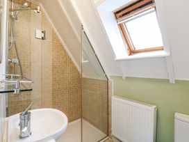 A bathroom with a sink shower area with glass door a radiator and a skylight window at Kingfisher Isleham