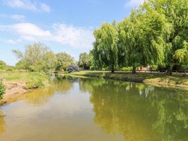 A river with green trees and grass on the banks under a blue sky at Kingfisher in Isleham