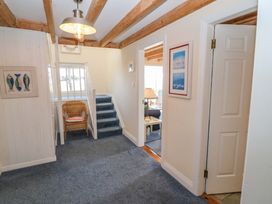 A hallway with a staircase and a wicker chair at Whispering Pines in Durrus, County Cork