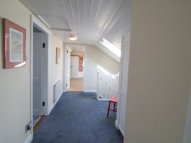 A hallway with a staircase and chair at Whispering Pines in Durrus, County Cork