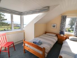 A bedroom with two beds and a red chair at Whispering Pines in Durrus, County Cork