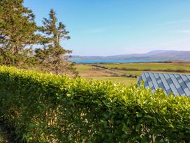 A view of a hedge with trees and water in the background at Whispering Pines in Durrus, County Cork
