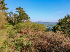 A view of bushes and trees overlooking water and hills at Whispering Pines in Durrus, County Cork