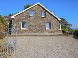 A stone house with windows and a gravel driveway at Whispering Pines in Durrus, County Cork