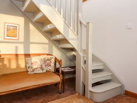 A staircase next to a wooden bench with floral cushions and a small table with magazines at The Apple House in Spaxton near Nether Stowey