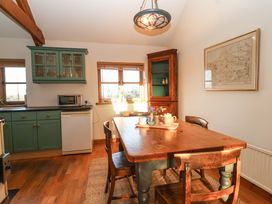 A kitchen and dining area with wooden table and chairs green cabinets and a microwave at The Apple House in Spaxton near Nether Stowey