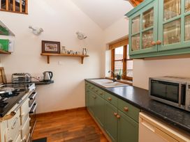 A kitchen with green cabinets a black countertop and wooden floor at The Apple House in Spaxton near Nether Stowey