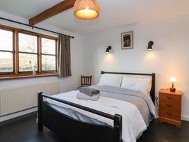 A bedroom with a double bed with folded towels bedside table with lamp wooden chair and window at The Apple House in Spaxton near Nether Stowey
