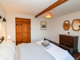A bedroom with a bed folded towels wooden door chest of drawers and two hexagonal mirrors at The Apple House in Spaxton near Nether Stowey
