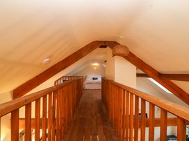 A loft bedroom with wooden railings and beams at The Apple House Spaxton near Nether Stowey