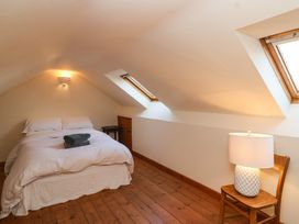 A bedroom with a bed side table lamp and angled windows at The Apple House in Spaxton near Nether Stowey
