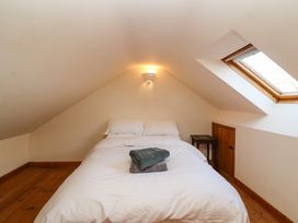 A bedroom with a bed white bedding towels on bed wooden floor skylight window and small wooden table at The Apple House in Spaxton near Nether Stowey