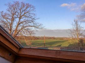 A view of a field and trees seen through a wooden framed window at The Apple House in Spaxton near Nether Stowey