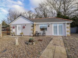 An outdoor area with a house and chairs at Old Colliery Cottage in Shilbottle