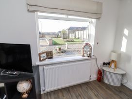 A living room with a television and a window overlooking the garden at Old Colliery Cottage in Shilbottle