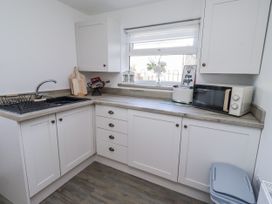 A kitchen with a sink, microwave and kitchen cabinets at Old Colliery Cottage in Shilbottle