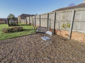 A garden with a swing chair and folding chair at Old Colliery Cottage in Shilbottle