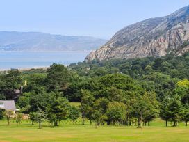 A landscape with trees green grass mountains and water at The Old Coach House in Conwy