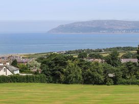 A coastal landscape with houses trees grassy field sea and hills at The Old Coach House in Conwy