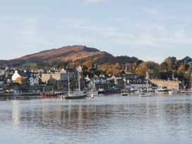 A harbor with boats and buildings with a hill in the background at The Old Coach House in Conwy