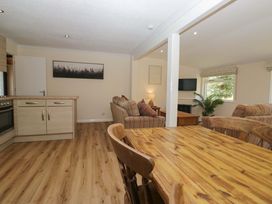 A living room with kitchen area and dining table at Beech Timber Lodge in Keswick
