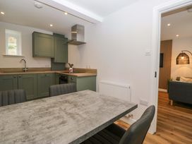 A kitchen with cabinets and a dining table at Riverside Cottage No 5 in Keswick