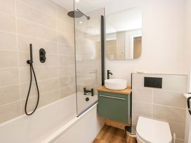 A bathroom with bathtub, shower, sink, and toilet at Riverside Cottage No 5 in Keswick