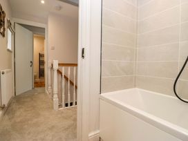 A bathroom with a bathtub and view of the staircase at Riverside Cottage No 5 Keswick