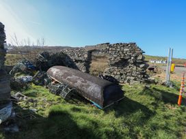 A boat and lobster traps near a stone wall outdoors at Sea View House in Tully, County Galway