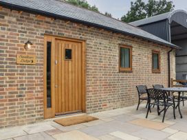 A brick exterior with a wooden door and two windows with brown frames and a black metal table with four chairs outside at Swallows Lodge in Dormansland