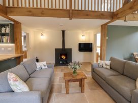 A living room with two sofas a wooden coffee table a fireplace and a wall mounted TV at Swallows Lodge in Dormansland