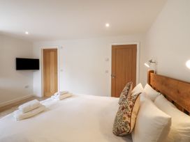 A bedroom with a bed with pillows and towels and two wooden doors and a wall mounted television at Swallows Lodge in Dormansland