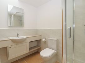 A bathroom with a sink and cabinet a toilet and a glass shower enclosure at Swallows Lodge in Dormansland