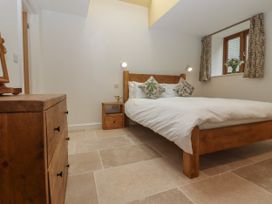 A bedroom with a wooden bed and bedside table with cushions and a window at Swallows Lodge in Dormansland