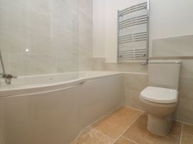 A bathroom with a white bathtub and toilet and a chrome towel radiator at Swallows Lodge in Dormansland