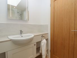 A bathroom with a white sink under a mirror and a wooden door with a towel hanging on a ring at Swallows Lodge in Dormansland
