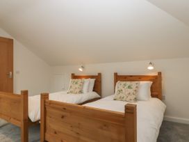 A bedroom with two wooden single beds with white bedding and floral cushions at Swallows Lodge in Dormansland