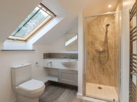 A bathroom with a toilet, sink under a skylight window, and a glass-enclosed shower at Swallows Lodge in Dormansland