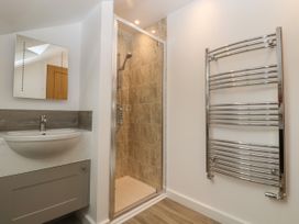 A bathroom with a sink and cabinet a wall mirror a tiled shower enclosure and a chrome towel radiator at Swallows Lodge in Dormansland