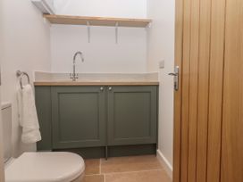 A small bathroom with a toilet towel ring and cabinet with sink at Swallows Lodge in Dormansland