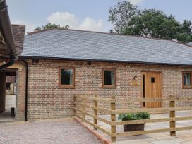An exterior view of a brick building with a wooden door and three windows at Swallows Lodge in Dormansland