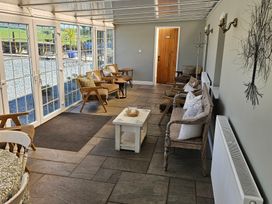 A conservatory with glass doors and wooden furniture at The Keepers Lodge in Boduan near Nefyn
