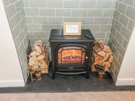 A living room with an electric stove and firewood at Millside View