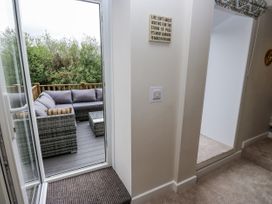 A living room with a door opening to a deck and a sofa at Millside View 
