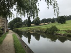 A path alongside a river with trees at Millside View in Kildwick