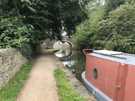 A canal with a narrowboat and a bridge at Millside View in Kildwick