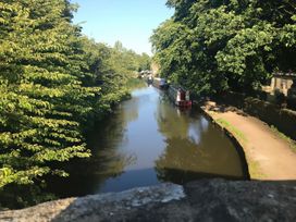 A canal with boats along the edge and trees at Millside View in Kildwick